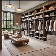 a large walk - in closet with lots of clothes on shelves, and a footstool