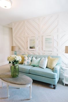 a living room filled with furniture and flowers on top of a coffee table in front of a wall