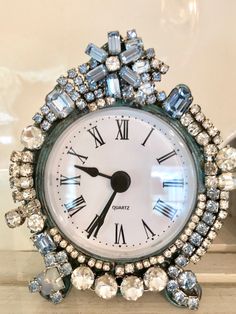 an ornate clock with roman numerals and blue crystals on it's face