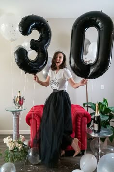 a woman holding balloons in the shape of numbers