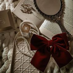 an open book with a red bow sitting on top of it next to other items