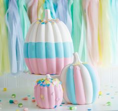 three colorful pumpkins sitting on top of a table next to confetti streamers