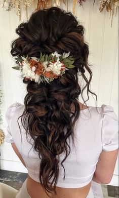 the back of a woman's head with flowers in her hair, wearing a white top