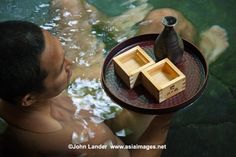 a man in the water holding a tray with two wooden boxes on top of it