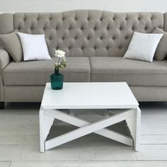 a living room with a couch, coffee table and two vases on the floor