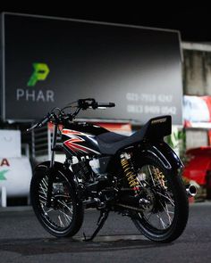 a black and red motorcycle parked in front of a large sign that says phar