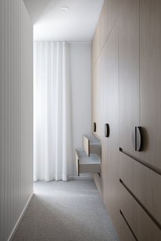 an empty room with white curtains and wooden cabinets in the foreground, along with a gray carpeted floor