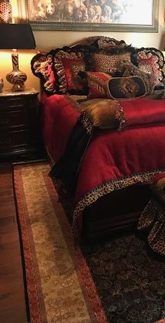 a bedroom with a large bed covered in red blankets and leopard print comforter, lamps on either side of the bed