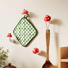 mushrooms are hanging on the wall next to a wooden spoon and spatula with red caps