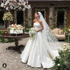 a woman in a wedding dress standing next to a table with flowers and cake on it