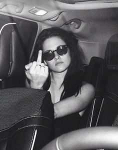 a woman sitting in the back seat of a car with her hand up to her face