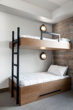 two bunk beds in a room with wood paneling and white sheets on the bed