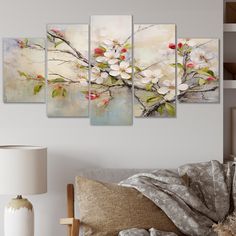 a living room area with a couch and paintings on the wall, including an apple blossom tree