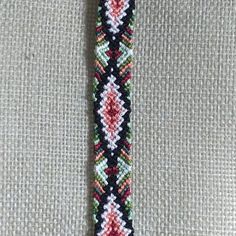 a close up of a tie on a white cloth with red, green and blue beads