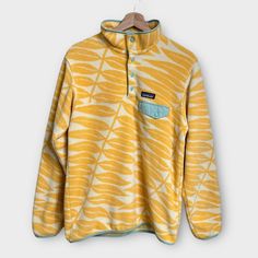 Patagonia Eucalyptus Fronds Vela Peach Synchilla Snap-T Fleece Pullover Size Medium Perfect For Layering And Outdoor Adventures This Fall! Hard To Find Limited Edition Style From Spring 2020. - Yellow Marigold And White With Green Trim; Vela Punch Color - Eucalyptus Fronds Leaf Pattern Throughout - Breathable Midweight 100% Recycled Polyester - Yoke Seam - Flap Chest Pocket - Snap Buttons //Approximate Measurements// Pit To Pit: 20” Length: 27” Fall Cozy Warm Hiking Outdoor Camping Casual Everyd Patagonia Fleece Retro Woman, Patagonia Retro X Fleece, Patagonia Fleece Synchilla, Colorful Patagonia Fleece, Patagonia Printed Fleece, Yellow Marigold, Patagonia Sweater, Patagonia Womens, Casual Everyday