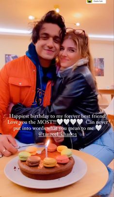 a man and woman sitting next to each other in front of a cake with candles on it