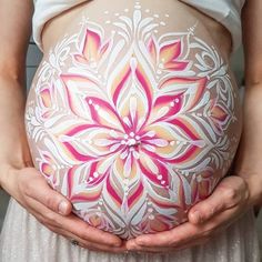 a pregnant woman holding her belly painted with flowers