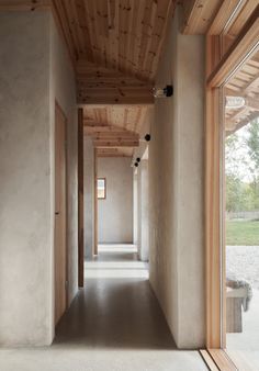 an empty hallway with wooden ceiling and windows on both sides, leading to another room