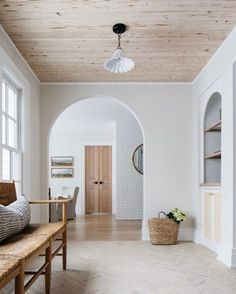 an archway leading to a living room with white walls and wood floors, along with a bench in front of the doorway