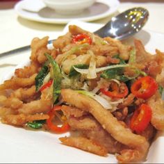 a white plate topped with fried food and a fork next to a bowl of soup