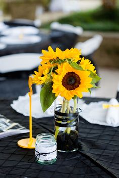 a sunflower in a vase on a table with other items and napkins around it