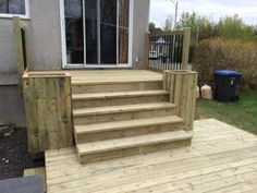 a wooden deck with steps leading up to the front door