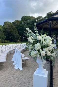 an outdoor ceremony setup with white flowers and chairs