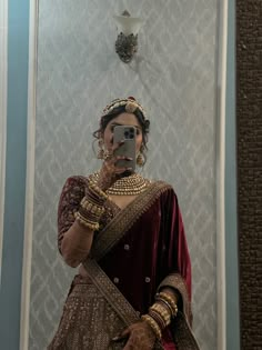 a woman taking a selfie in front of a mirror wearing a bridal outfit