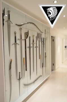 a large display case filled with lots of different types of swords on glass walls in a hallway