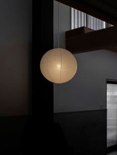 a white light hanging from the ceiling in a room with dark walls and flooring