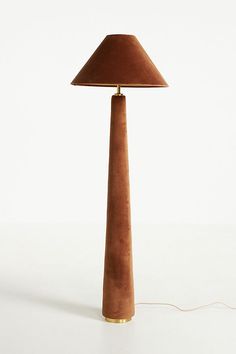 a lamp with a brown shade on it sitting on top of a white table next to a cord