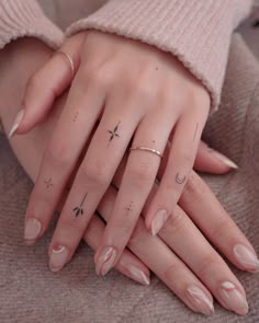 a woman's hand with two fingers and three stars on the middle finger, while she is wearing a pink sweater