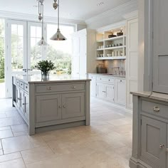 a large kitchen with white cabinets and marble counter tops