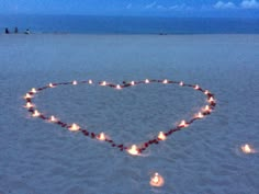 a heart made out of candles in the sand