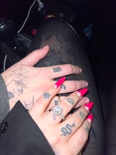 a woman with red nails and tattoos on her arm sitting in the back seat of a car