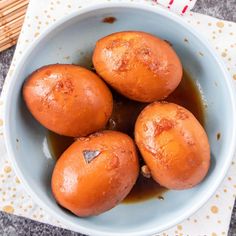 four peeled oranges in a blue bowl on a table next to chopsticks