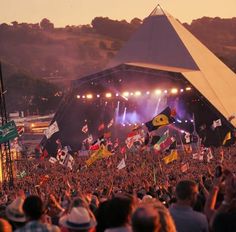 a large group of people standing on top of a stage with flags in front of them