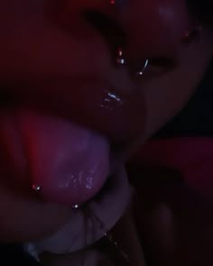 a close up of a person with piercings on their nose and tongue in the dark