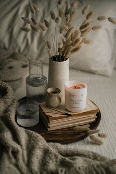 a tray with candles and books on top of a bed next to a candle holder