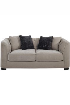 a white couch with two black pillows on it's back and the seat upholstered