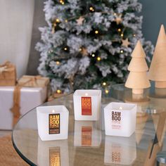 three candles sitting on top of a glass table next to a christmas tree and presents