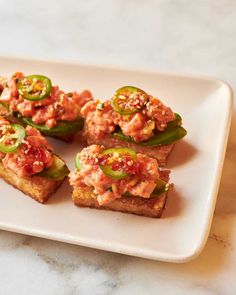 small pieces of food on a white plate with pepper and jalapeno peppers