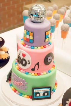 a multi - tiered cake decorated with disco balls, music and cassette tape recorders