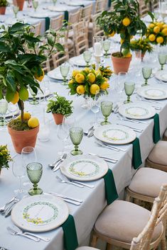 a table set with lemons and greenery for an outdoor dinner or party event