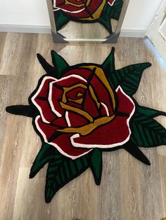 a red rose rug sitting on top of a hard wood floor next to a mirror