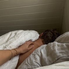 a woman laying in bed with her head on the pillow