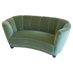 a green curved couch sitting on top of a white floor