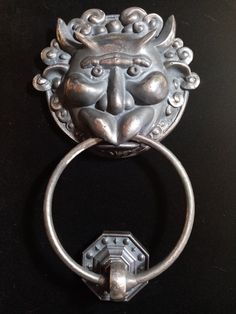 a metal lion head door knockle on a black surface with a hexagonal ring