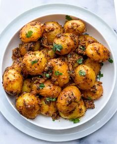 a white plate topped with potatoes covered in seasoning and garnished with parsley