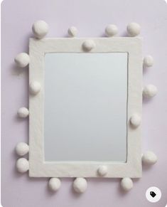 a mirror that has some balls on the top of it and is hanging up against a wall